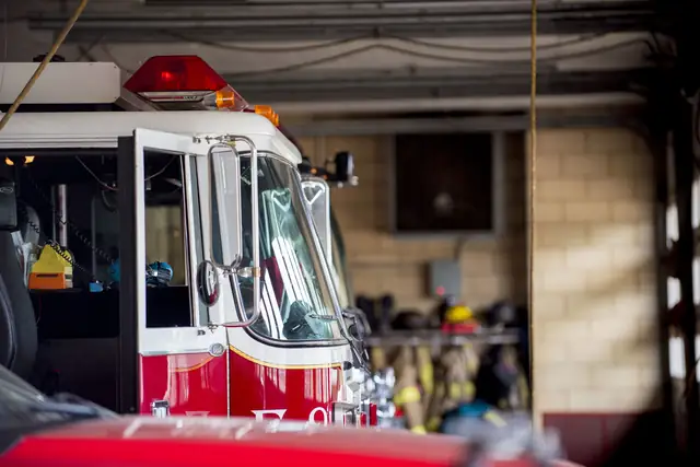 A fire engine parked in the station bay, turnout gear on the rack behind it
